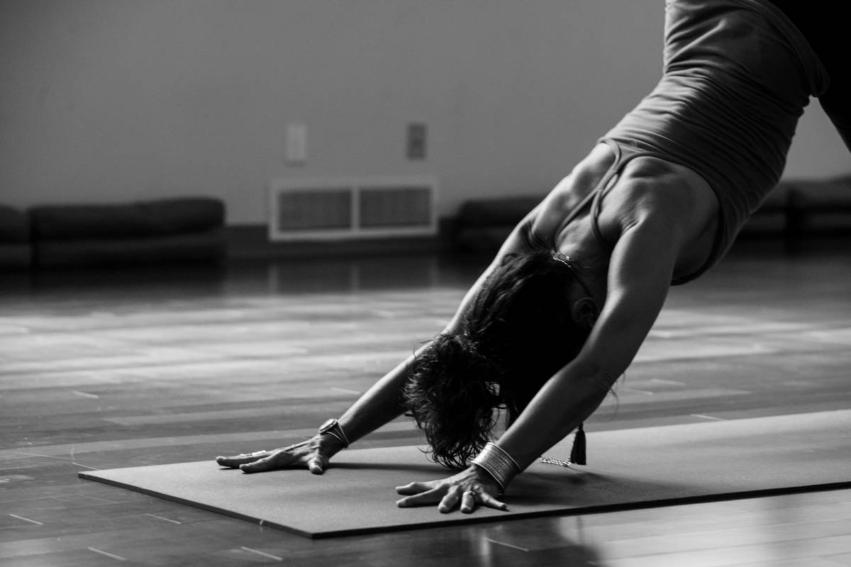 A woman practicing pilates on a mat indoors with sunlight streaming through windows